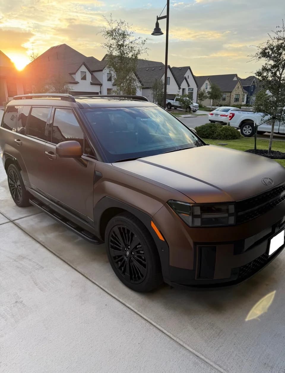 Bronze Hyundai SUV parked in a driveway at sunset